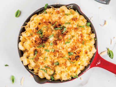 Finished mac-n-cheese in a red cast-iron pan on a white table.